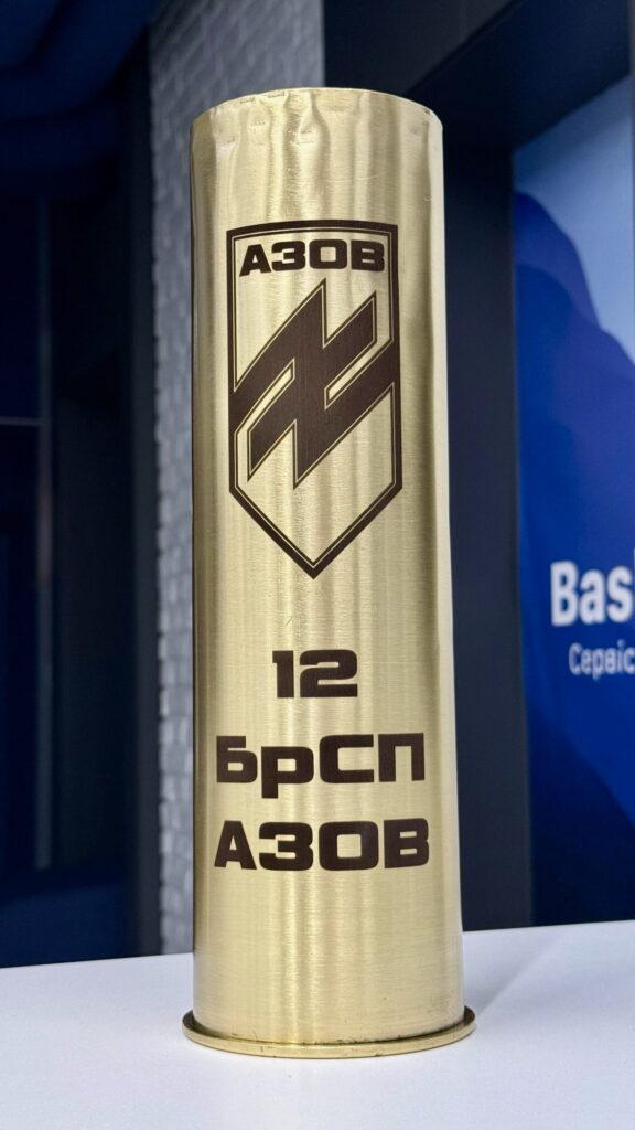 Гільза з великим щитом АЗОВ та написом «12 БрСП АЗОВ». Використовується як офіційний представницький подарунок від командування.