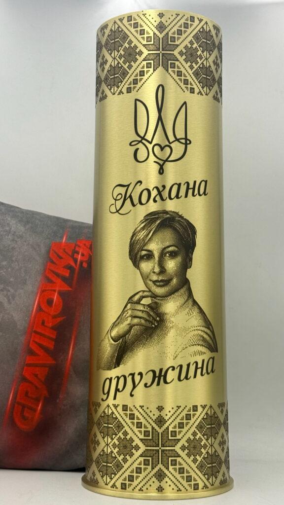 Точне реалістичне відтворення фото дружини у техніці гравірування. Детальна промальовка рис обличчя, світлотінь, природні деталі — і все це на золотистій латуні. Доповнено тризубом-серцем та орнаментом вишиванки.
