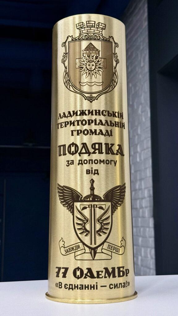 Лазерне гравіювання на латунній гільзі: подяка від 77 ОАеМБр Ладижинській Територіальній Громаді з гербом міста та шевроном бригади