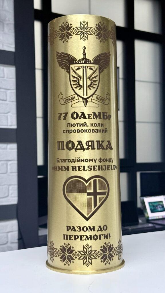 Гравійована латунна гільза — подяка від 77 ОАеМБр благодійному фонду «НММ Helsienjelp» з написом «Разом до перемоги!»