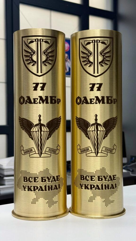 Дві латунні гільзи з гравіюванням символіки 77 ОАеМБр та написом «ВСЕ БУДЕ УКРАЇНА!» — вигляд спереду