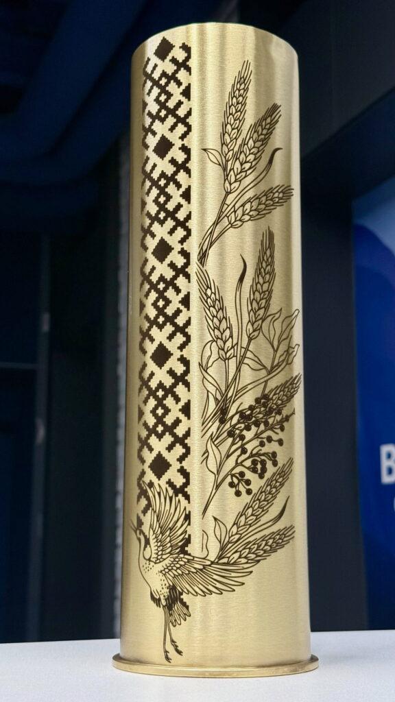 Вертикальна смуга пиксельного орнаменту вишиванки зліва, праворуч — розкішна композиція з колосків пшениці, гілочок калини та журавля у польоті. Вишукана і символічна.