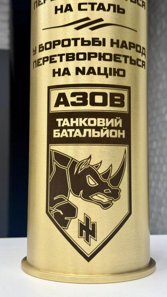 Деталізований крупний план: щит із носорогом, напис «АЗОВ. ТАНКОВИЙ БАТАЛЬЙОН» і руни ᛜᛜ. Гравіювання передає кожну лінію ілюстрації без втрат.