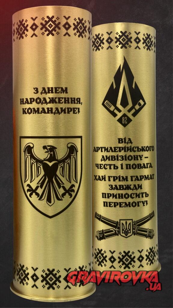 Дві сторони гравійованої гільзи — силезький орел на щиті з написом «З Днем народження, Командире!» та зворотна сторона з шевроном артилерійського дивізіону 82-ї бригади, схрещені гармати з тризубом, «Хай грім гармат завжди приносить перемогу!» gravirovka.ua Геральдичний орел займає половину лицьової поверхні — потужний і благородний образ. Зворотна сторона — артилерійська символіка і вогнеметний тост від дивізіону.
